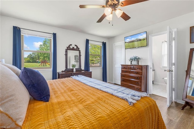 bedroom featuring wood finished floors, baseboards, ensuite bathroom, and a ceiling fan
