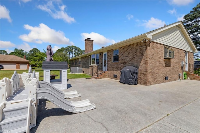rear view of house featuring a chimney, brick siding, entry steps, and a patio area