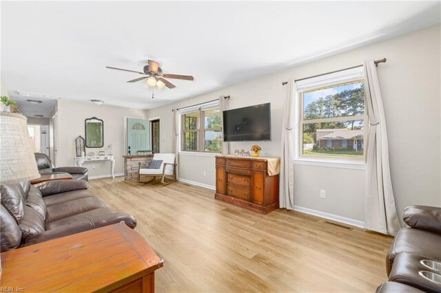 living area featuring baseboards, ceiling fan, and light wood-style flooring