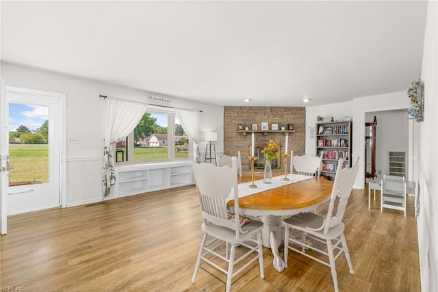 dining area featuring light wood finished floors and wainscoting