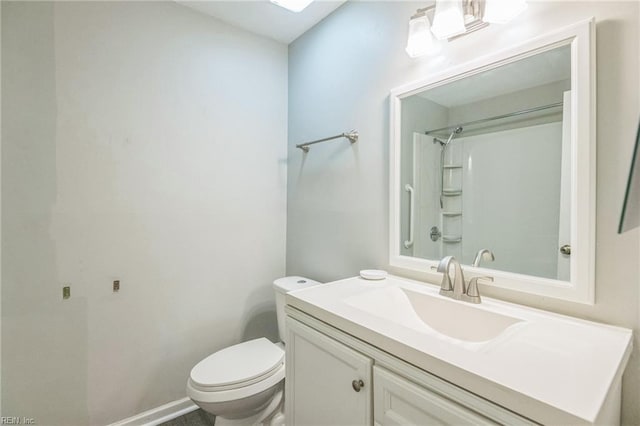bathroom featuring toilet, vanity, a shower, and baseboards