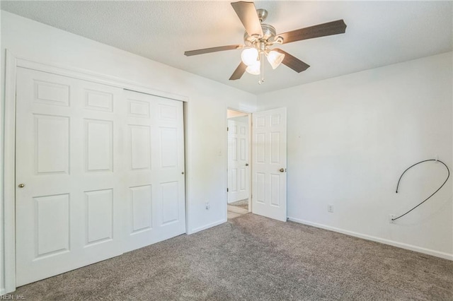 unfurnished bedroom with carpet flooring, a closet, baseboards, and ceiling fan