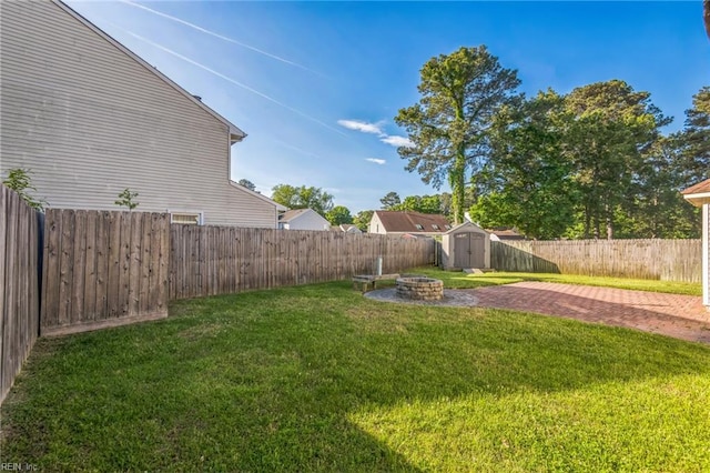 view of yard with a storage shed, an outdoor fire pit, an outdoor structure, and a patio area