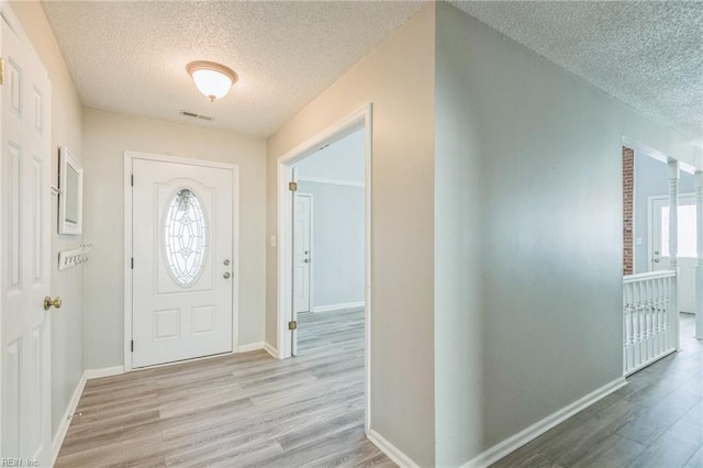 foyer with a textured ceiling, wood finished floors, and baseboards