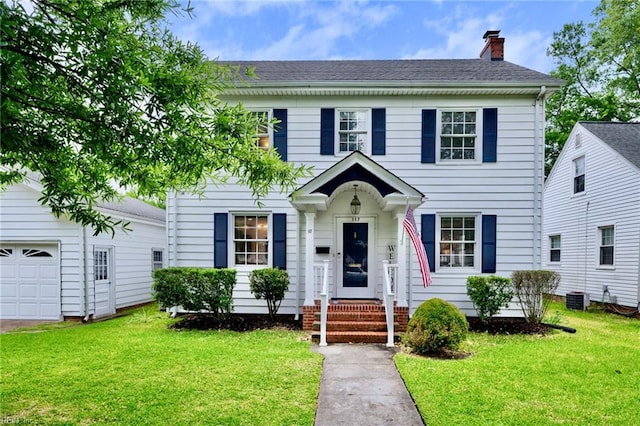 colonial inspired home with a chimney, a front yard, cooling unit, and a garage
