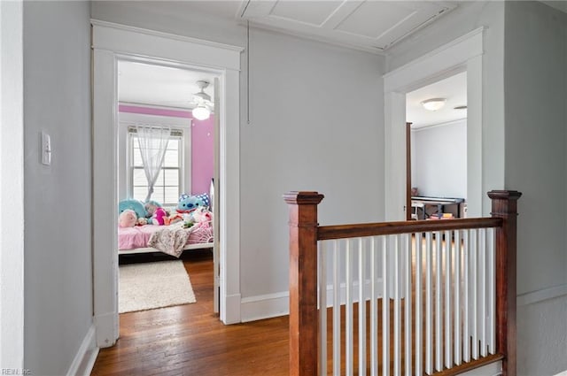 hall featuring wood finished floors, baseboards, and attic access