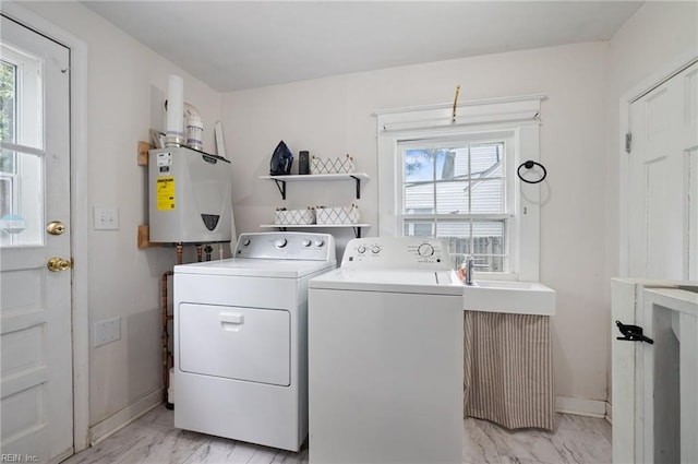 laundry area featuring washer and dryer, water heater, light marble finish flooring, and baseboards