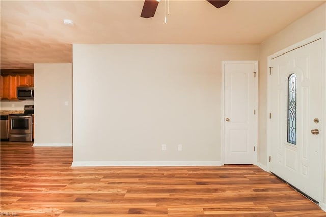 entryway with ceiling fan, light wood finished floors, and baseboards
