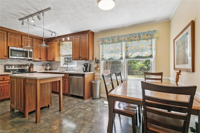 16 Windy Point Dr, Poquoson, VA 23662 - kitchen with appliances with stainless steel finishes, brown cabinetry, decorative backsplash, a textured ceiling, and crown molding