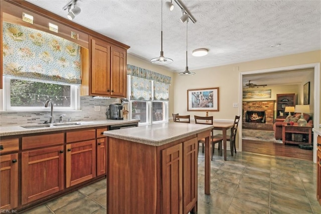 16 Windy Point Dr, Poquoson, VA 23662 - kitchen featuring rail lighting, a sink, light countertops, a fireplace, and pendant lighting