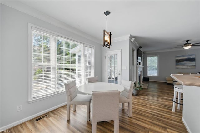 dining room with crown molding, baseboards, a fireplace, and wood finished floors