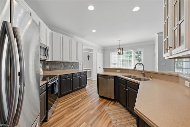 kitchen with appliances with stainless steel finishes, a sink, ornamental molding, healthy amount of natural light, and light countertops