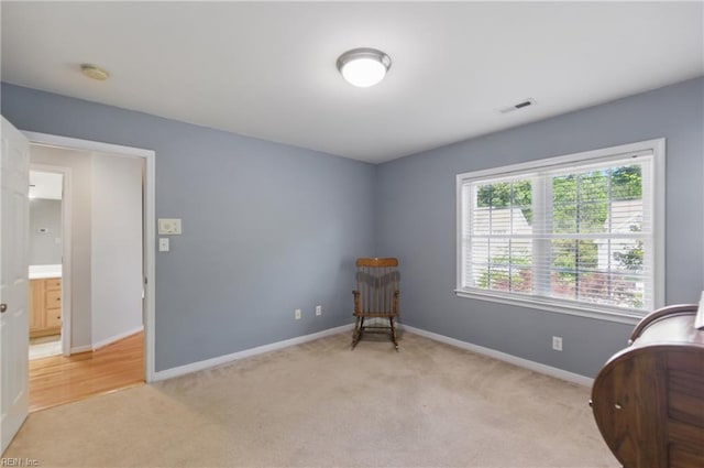 sitting room featuring light colored carpet and baseboards