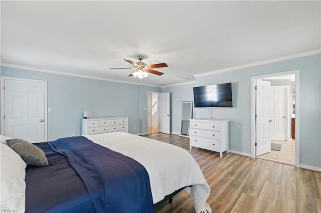 bedroom featuring light wood finished floors, ornamental molding, baseboards, a ceiling fan, and ensuite bathroom
