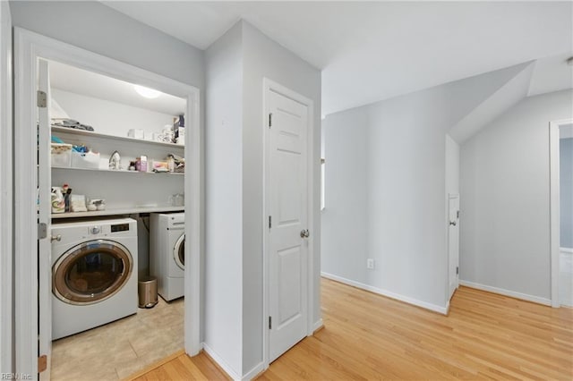 laundry area featuring light wood-type flooring, washing machine and clothes dryer, and baseboards