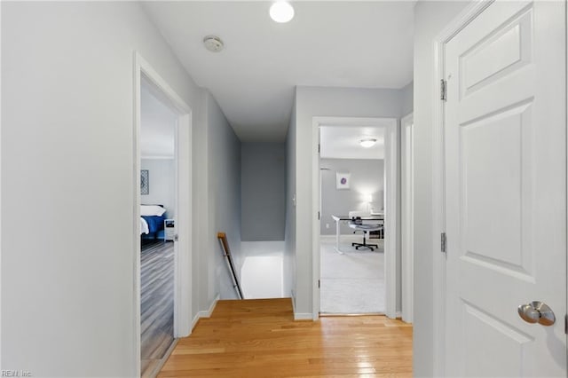 hall featuring an upstairs landing, light wood finished floors, and baseboards