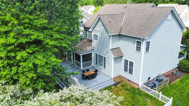 rear view of property with a sunroom, roof with shingles, and a deck