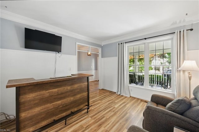 living room featuring wainscoting, light wood-style floors, and crown molding