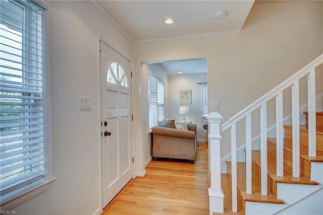 entrance foyer with light wood finished floors, stairs, and crown molding