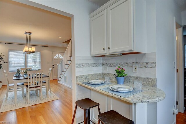 kitchen featuring light wood-type flooring, white cabinets, tasteful backsplash, a chandelier, and recessed lighting