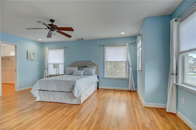 bedroom with light wood-style floors, baseboards, a spacious closet, and recessed lighting
