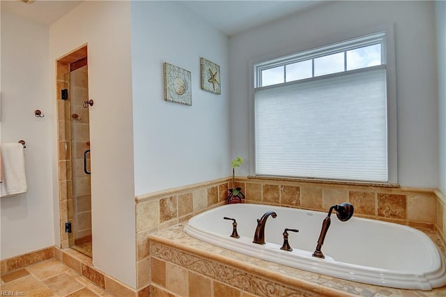 bathroom with a shower stall, a bath, and stone finish floors