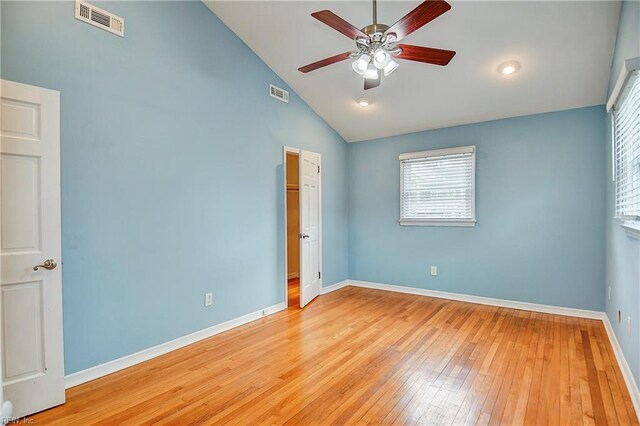 unfurnished bedroom with wood-type flooring, multiple windows, baseboards, a ceiling fan, and high vaulted ceiling