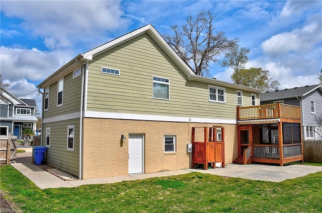 rear view of house featuring brick siding, a patio, and a wooden deck