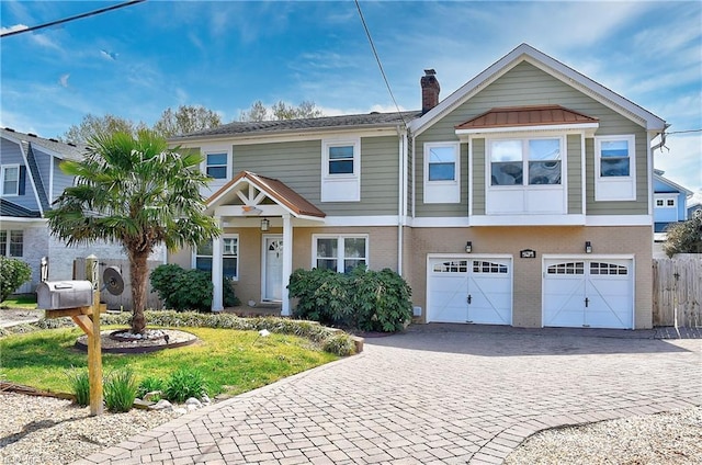 view of front of property with decorative driveway, a chimney, brick siding, an attached garage, and fence