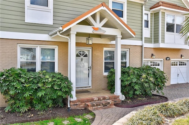 doorway to property featuring brick siding and an attached garage