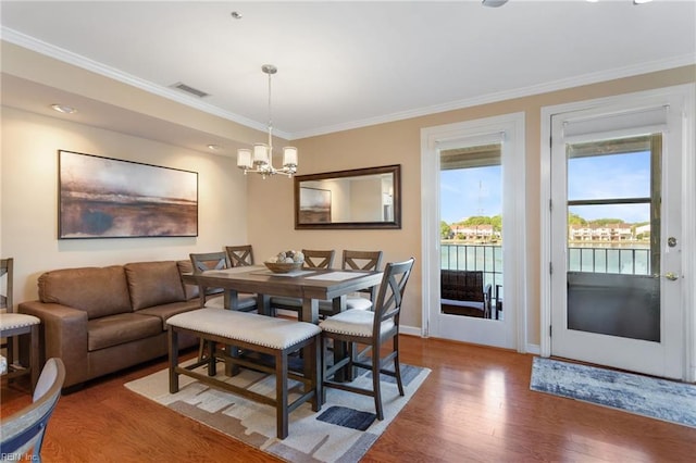 dining area with wood finished floors, a chandelier, crown molding, and baseboards