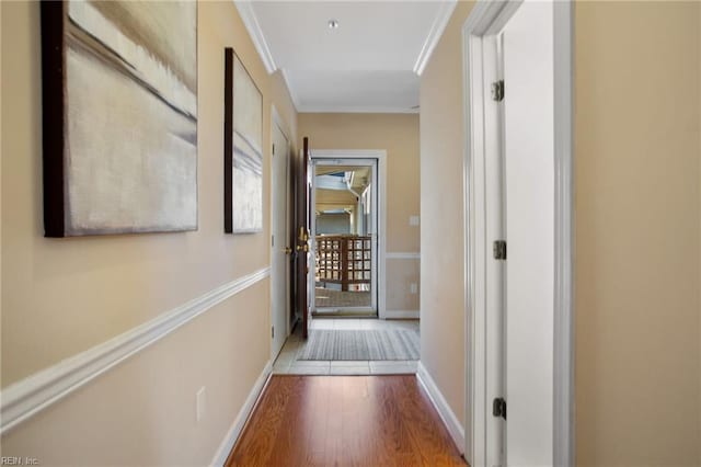 hallway with wood finished floors, baseboards, and crown molding