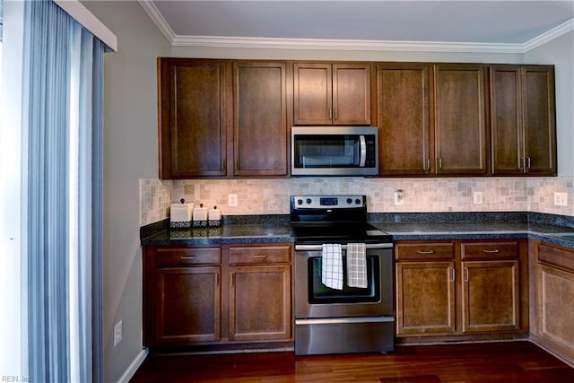 kitchen featuring stainless steel appliances, ornamental molding, dark countertops, and decorative backsplash