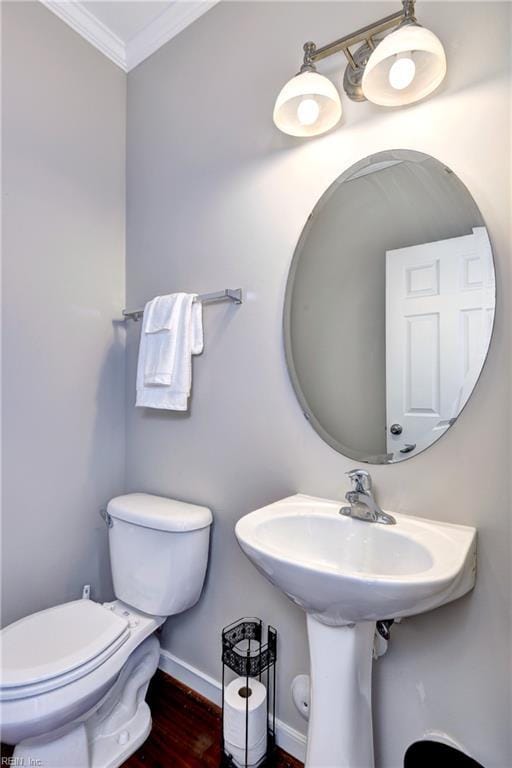 bathroom with ornamental molding, toilet, baseboards, and wood finished floors