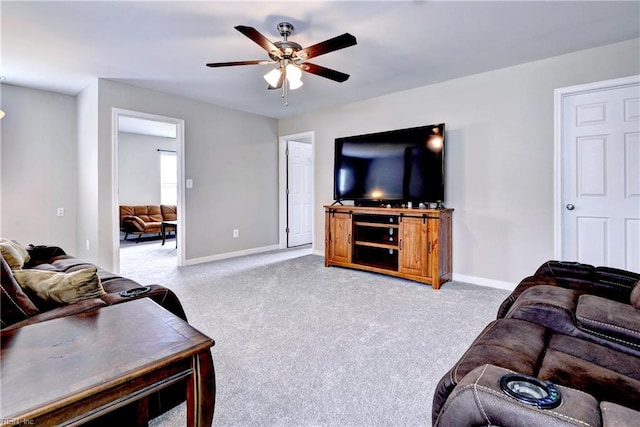 living area featuring a ceiling fan, baseboards, and light colored carpet
