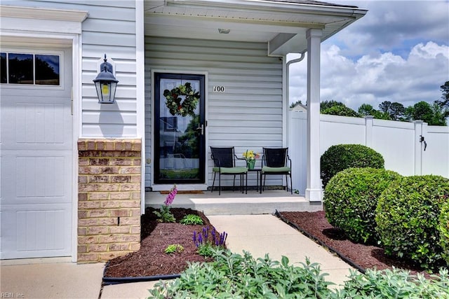 view of exterior entry with a porch and fence