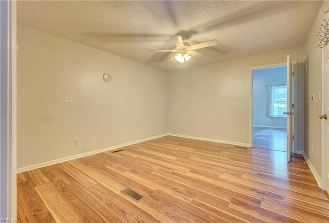 spare room with a textured ceiling, a ceiling fan, light wood-style floors, and baseboards