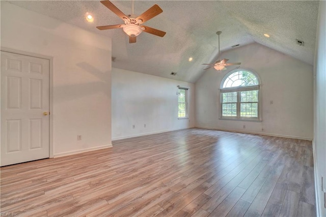 empty room featuring a ceiling fan, lofted ceiling, light wood-style floors, a textured ceiling, and baseboards
