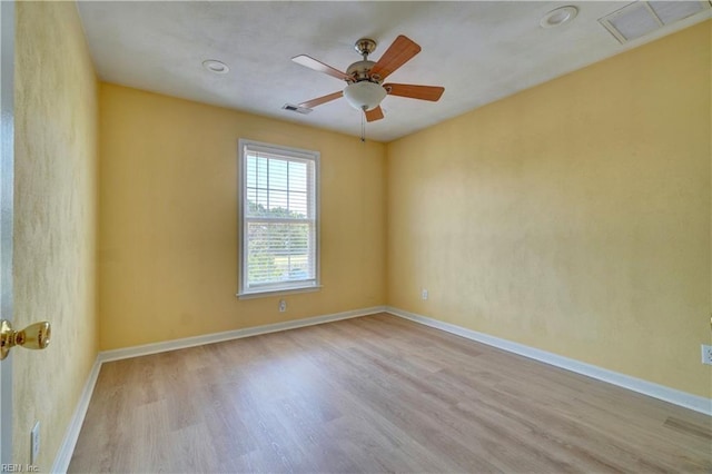 empty room with wood finished floors, a ceiling fan, and baseboards