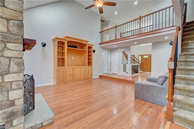living room featuring stairs, high vaulted ceiling, a ceiling fan, wood finished floors, and baseboards