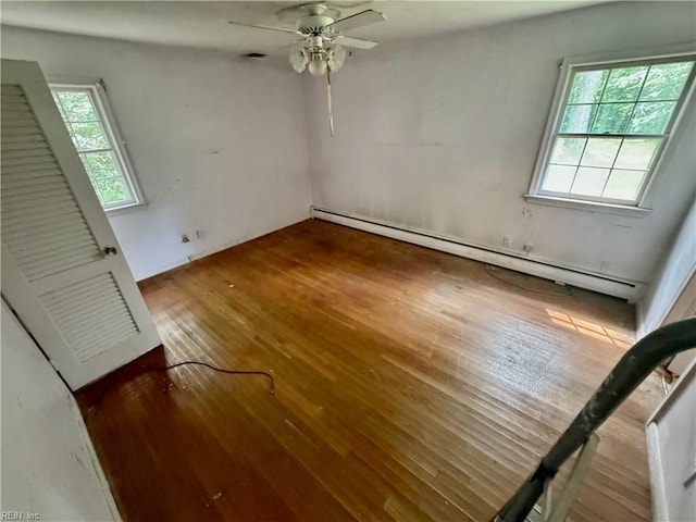 empty room featuring baseboard heating, ceiling fan, and wood-type flooring