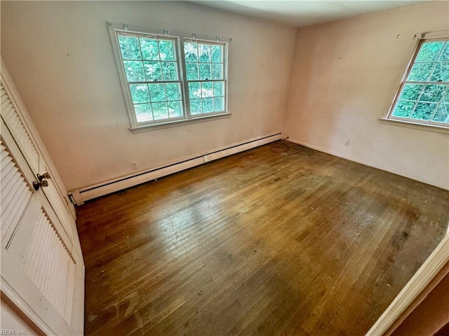 unfurnished room with baseboard heating, hardwood / wood-style floors, and plenty of natural light