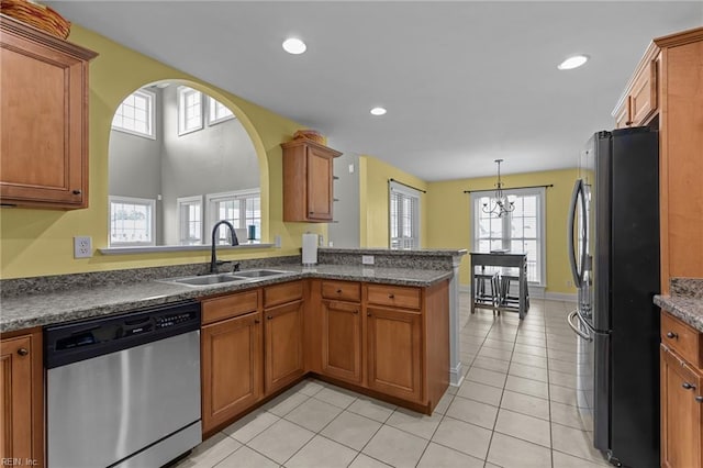 110 Lands End Dr, Elizabeth City, NC 27909 - kitchen with stainless steel dishwasher, freestanding refrigerator, a sink, a chandelier, and brown cabinets