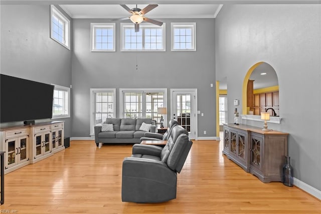 110 Lands End Dr, Elizabeth City, NC 27909 - living room featuring ceiling fan, crown molding, baseboards, light wood-style flooring, and a high ceiling