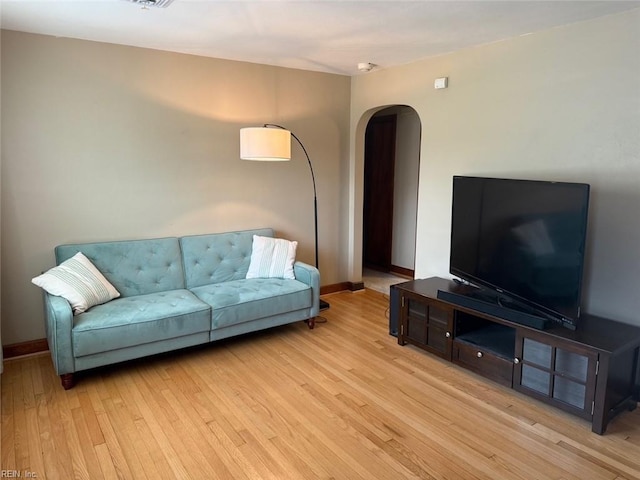 living room featuring arched walkways, wood finished floors, and baseboards