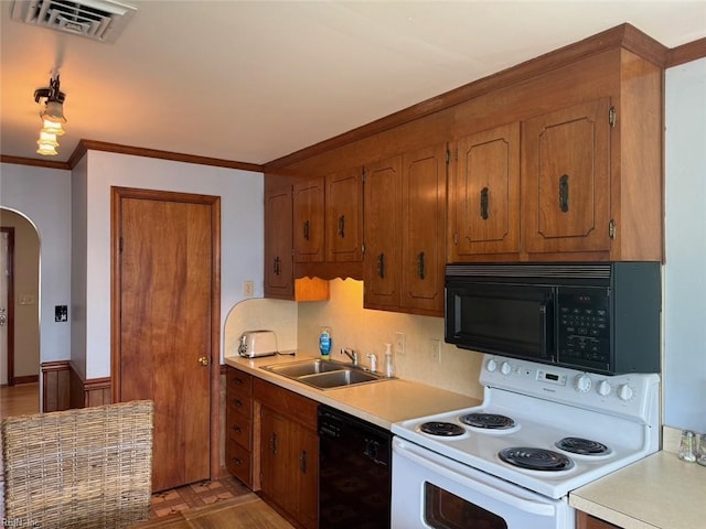 kitchen featuring black appliances, a sink, light countertops, arched walkways, and ornamental molding