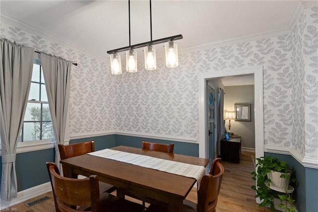dining room featuring wallpapered walls, crown molding, and wood finished floors
