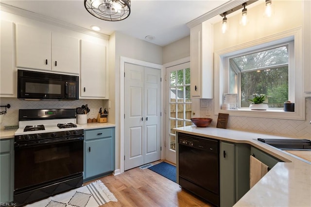kitchen featuring black appliances, light countertops, light wood-type flooring, and decorative backsplash
