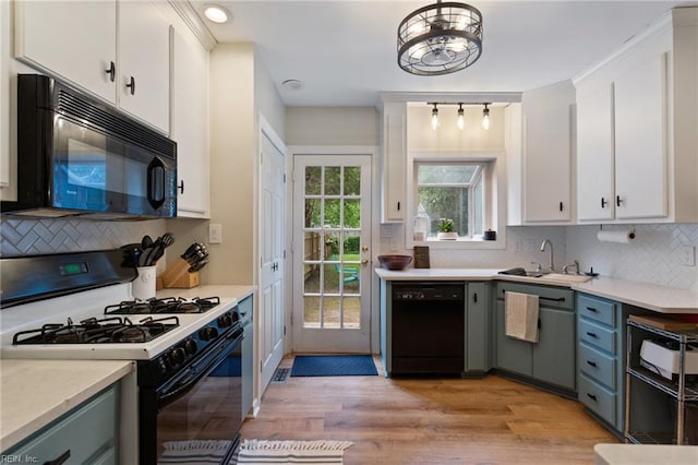 kitchen with black appliances, a sink, white cabinets, and backsplash