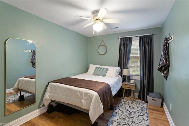 bedroom with wood finished floors, baseboards, and ceiling fan